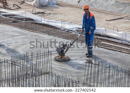 Renaissance Construction worker produces the grout and finish wet concrete with a special tool. Float blades. For smoothing and polishing concrete, concrete floors.Belarus, Minsk, November 1.2014