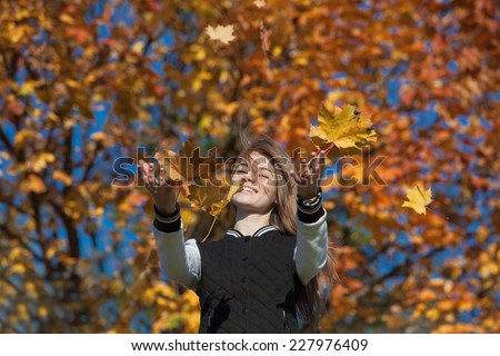 Girl walking in autumn park with yellow leaves fall