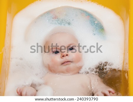 Boy baby 4 months of age is bathed in the bath with foam on head