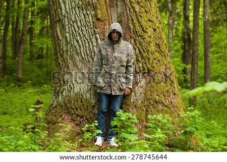 a man near a huge trunk age 600 years old oak tree in the forest