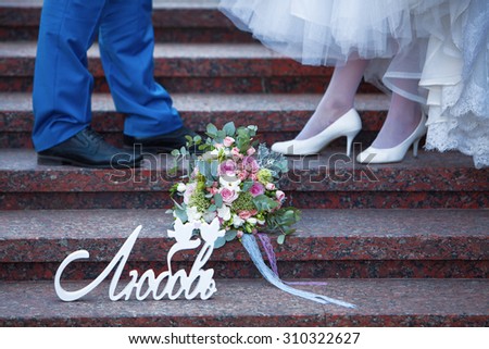 Bridal bouquet and the word love in Russian on the steps of the bride and groom shoes