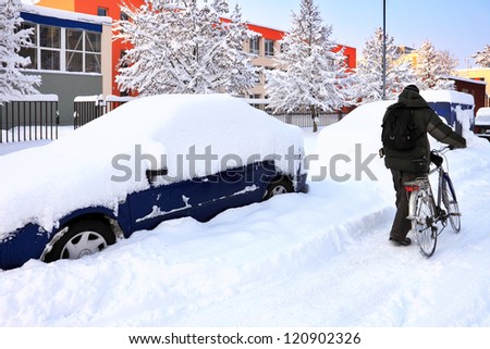 snow-covered car lot in town with cyclist