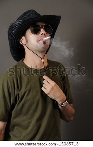 Portrait of young trendy man smoking with cowboy hat