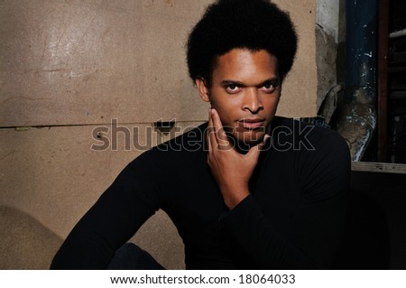 Portrait of young trendy african male posing over grunge background