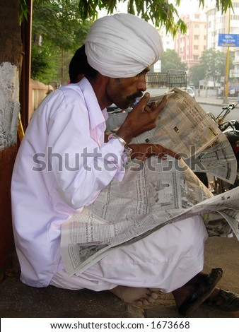 a man in white sipping tea outside a tea stall in indian village