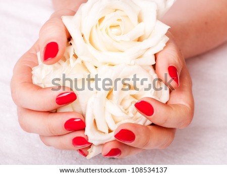 close-up of female hands with red nail polish on the background  flowers