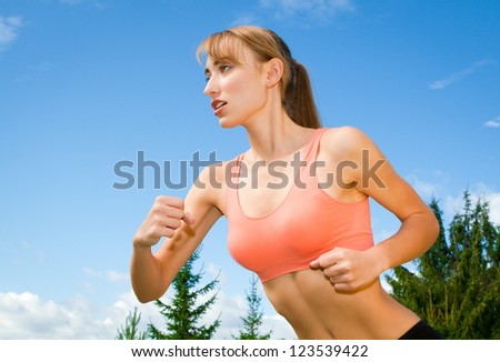 young woman playing sports, jogging outdoors, recreation, background blue sky