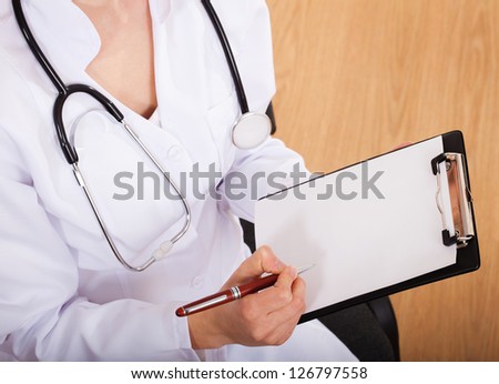 Female doctor showing blank clipboard