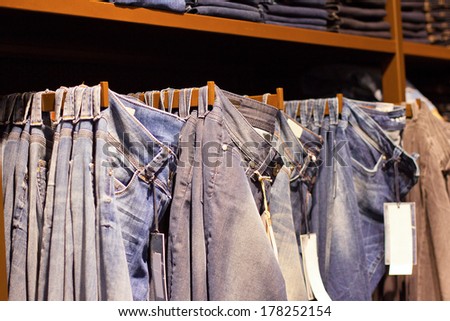 Fashion clothes on the shelves in the store. Jeans, shirts, pants hanging on hangers in the fashion store. Storefront, sale, shopping