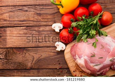 Raw meat for barbecue with fresh vegetables and mushroom on wooden surface, menu cooking recipes. Food, raw steak, beef steak bbq, tomatoes, peppers, spices for cooking meat. Free space for text.