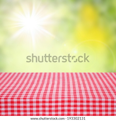 Canvas texture or background on table. Red checked tablecloth view from top. Empty tablecloth for product montage. Sunny summer day outdoors. Free space for your text