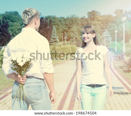 Young beautiful couple in love outdoors. Young man gives flowers to beautiful woman. Romance happy couple