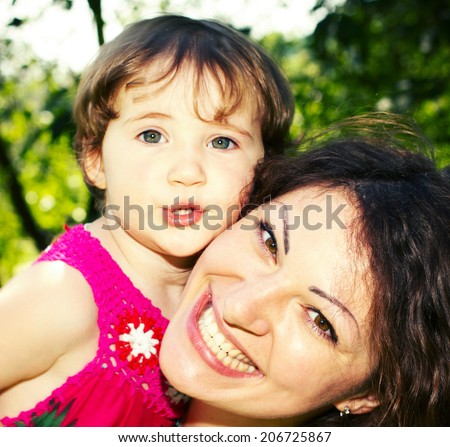 Portrait of happy little girl who embraces his mother. Face of beautiful mother and daughter close-up. Outdoor portrait of happy family. Joy mom and baby.