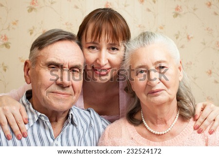 Happy family. Portrait of elderly couple and adult daughter happily looking at camera. Senior man, woman with their caregiver at home.