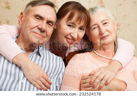 Happy family. Portrait of elderly couple and adult daughter happily looking at camera. Senior man, woman with their caregiver at home.