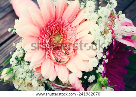 Flowers. Wedding bridal bouquet of white roses and pink lilies with wedding rings on  wooden table, close-up