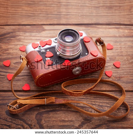 Retro Camera with red hearts on a wooden background. Valentine\'s Day greeting card