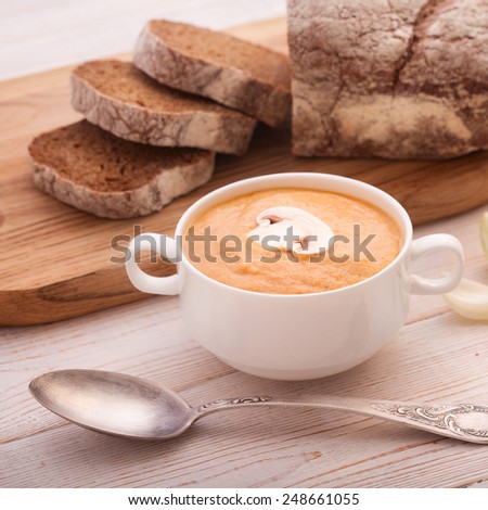 bowl of soup and bread on wooden table.