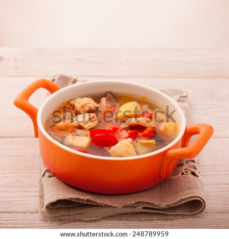 Fresh chicken soup with vegetables on white wooden table. Cutlery on a linen tablecloth. rustic style