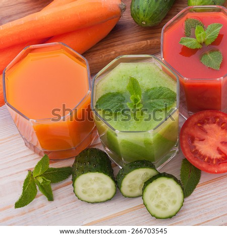 Tomato, cucumber, carrot juices and vegetables on white wooden table top view