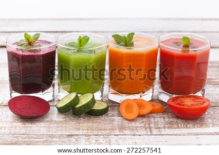 Four summer drink vegetable smoothies. Tomato, cucumber, carrot, beet Juices and vegetables on white wooden table