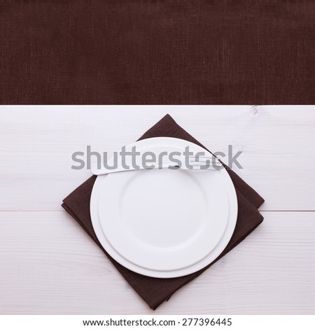 Empty plates and cutlery on table cloth on wooden table for dinner. Top view square. Flat mock up for design.