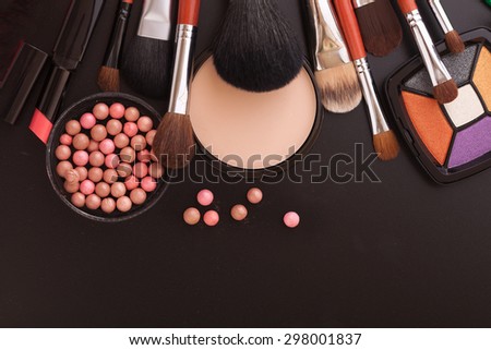 Colorful frame with various makeup products on black texture background. An unusual view, top view, mock up for design. Selective focus.