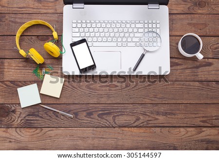Mix of office supplies and gadgets on wooden desk background. View from above.