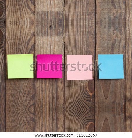 Multicolored paper stickers note on wooden background. Blank forms for workers notes
