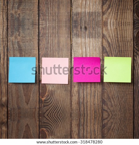 Multicolored paper stickers note on wooden background. Blank forms for workers notes