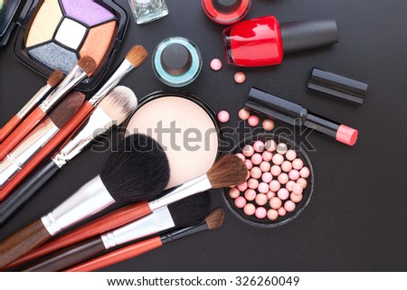 Various makeup products on dark background with copyspace. Cosmetics make up artist objects: lipstick, eye shadows, eyeliner, concealer, nail polish, powder, tools for make-up