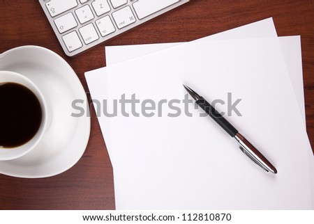 cup of coffee keyboard piece of paper and pen on the table