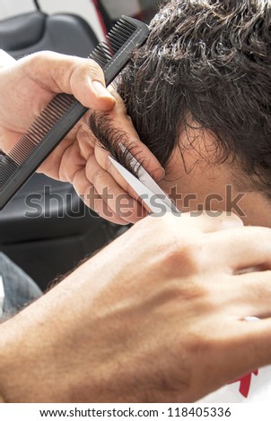Barber cutting hair with scissors at a barber shop