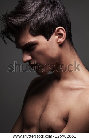 Man undressing. Handsome young muscular man taking off his tank
