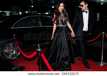 Sexy couple in the car. Hollywood star. Fashionable pair of elegant people at night city street.