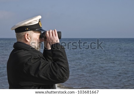 Sailor with binoculars observing the sea in calm weather