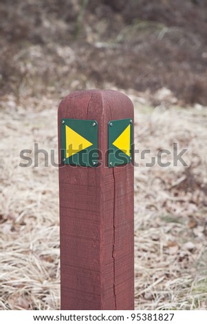 Hiking sign. Yellow arrows on a red pole.