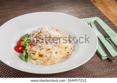 Traditional Italian spahgetti Bolognaise or Bolognese with cooked pasta noodles topped with a tomato based meat sauce garnished with fresh basil, parmesan and cherry tomatoes on white plate