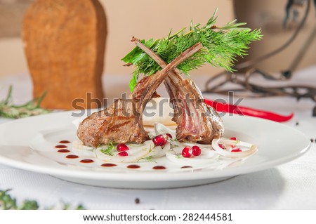 Grilled rack of lamb with fresh onion rings, greens and pomegranate seeds in oriental restaurant