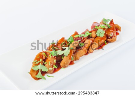 Traditional Japanese dish - chicken tempura with spicy sauce decorated by parsley and chives on a white plate isolated