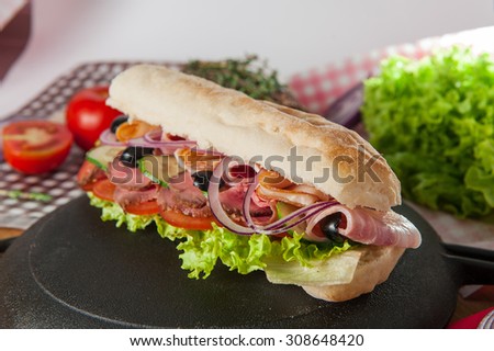 Close up Fresh sandwich with wheat bun, ham, bacon and vegetables in a pan on the table with colourfull ingredients
