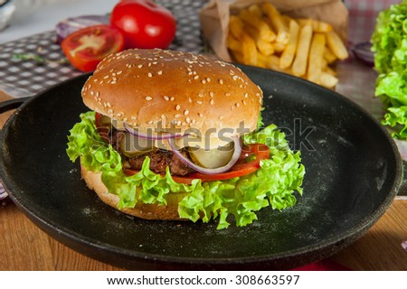 Close up tasty Burger with  beef meat, cheese, lettuce and vegetables  in the pan on the table  arounded some ingredients