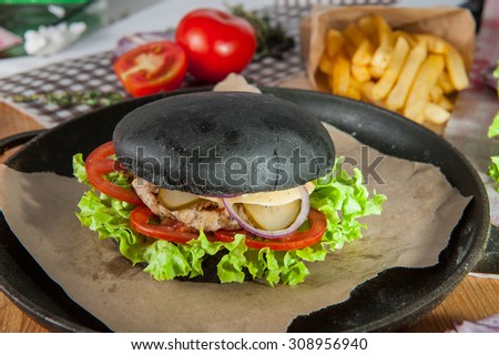 Close up  Black burger with pork chops, cheese and vegetables  in the pan on the table  arounded some ingredients