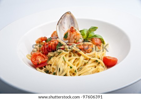 Close up  Plate of Italian Seafood Pasta with clam, shrimps, cherry tomatos and basil decorated with shell mussel on the white plate isolated