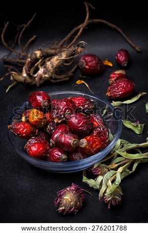 berries are dried rose hips and herbs on black background