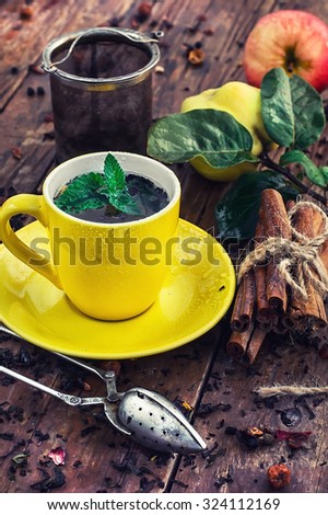 Brew tea.Cup of brewed herbal tea on wooden background strewn with tea leaves