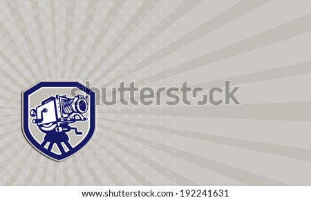 Business Card illustration of a vintage movie film camera viewed from low angle front set inside shield crest shape done in retro  style.