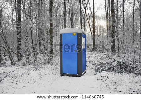 Blue mobile toilet cabin in a snow covered forest