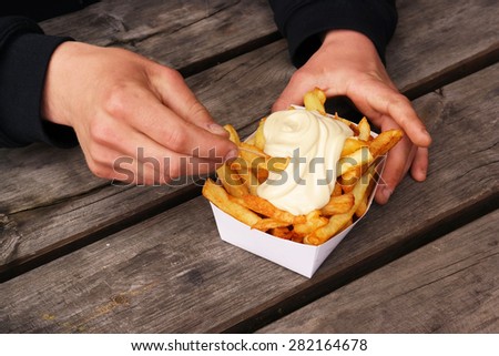 Belgian pommes frites. Hands with a tray of Belgian fries and mayonnaise on top.