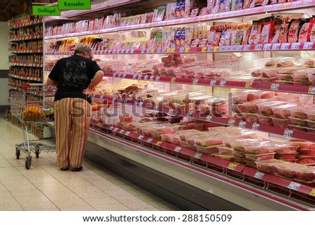 GOCH, GERMANY - MAY 6: Customer selecting packaged meat in refrigerated section of a Kaufland hypermarket. Photo taken on May 6, 2015 in Goch, Germany